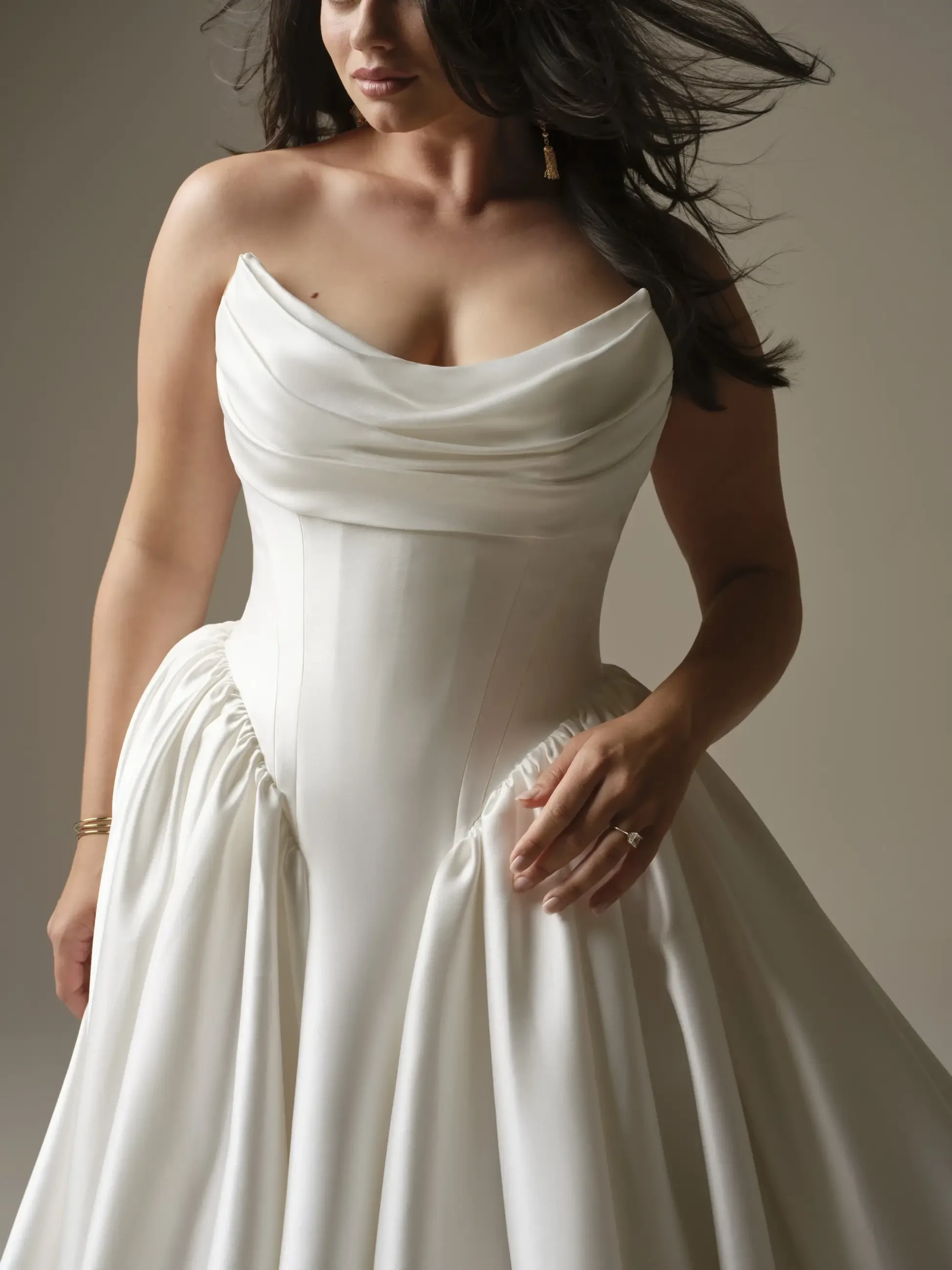 A woman wearing a strapless white dress with elegant draping. The dress has a fitted bodice and a flowing skirt.