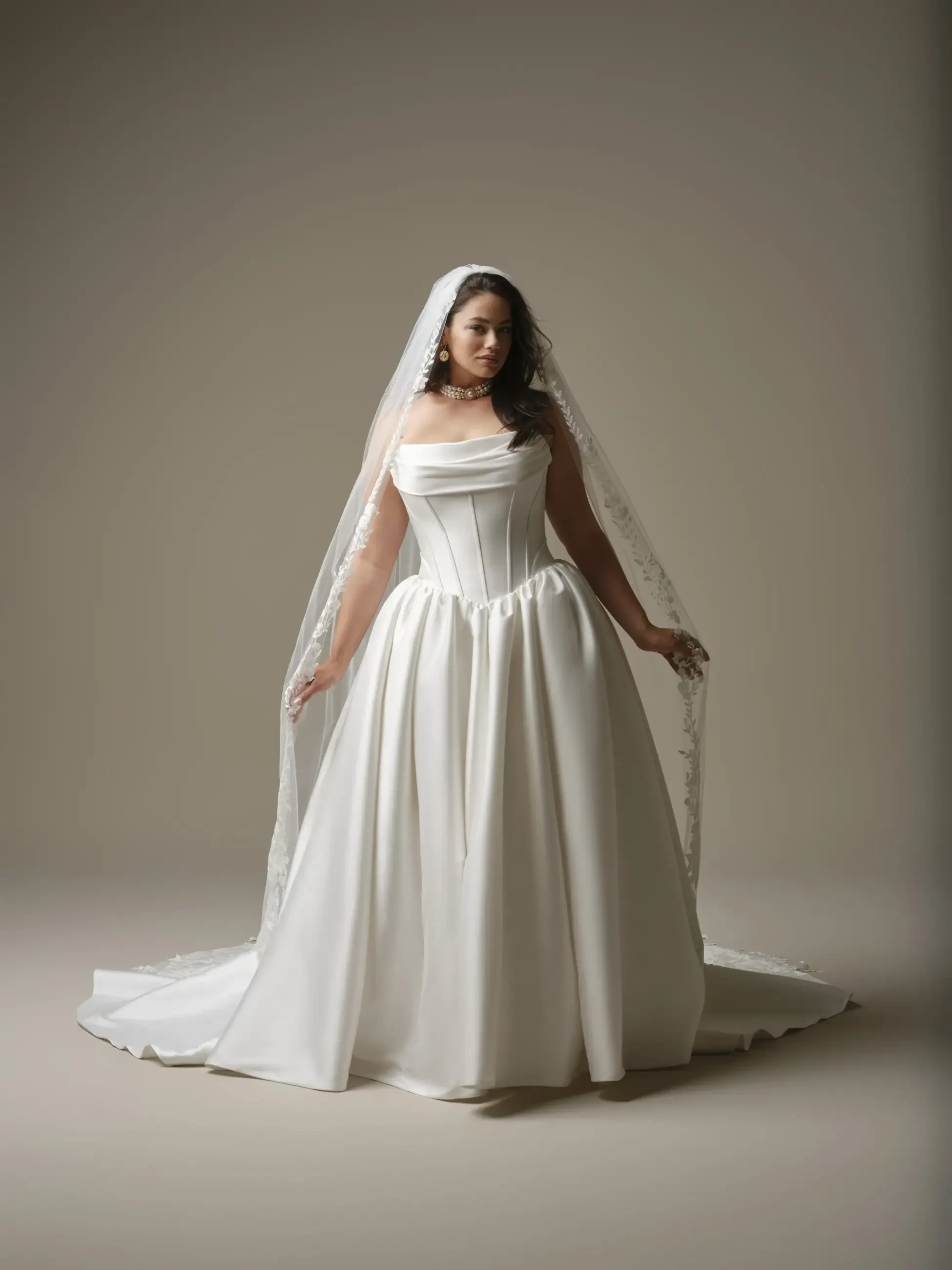 A bride wearing a classic white wedding dress with a fitted bodice and a full skirt, topped with a long veil.