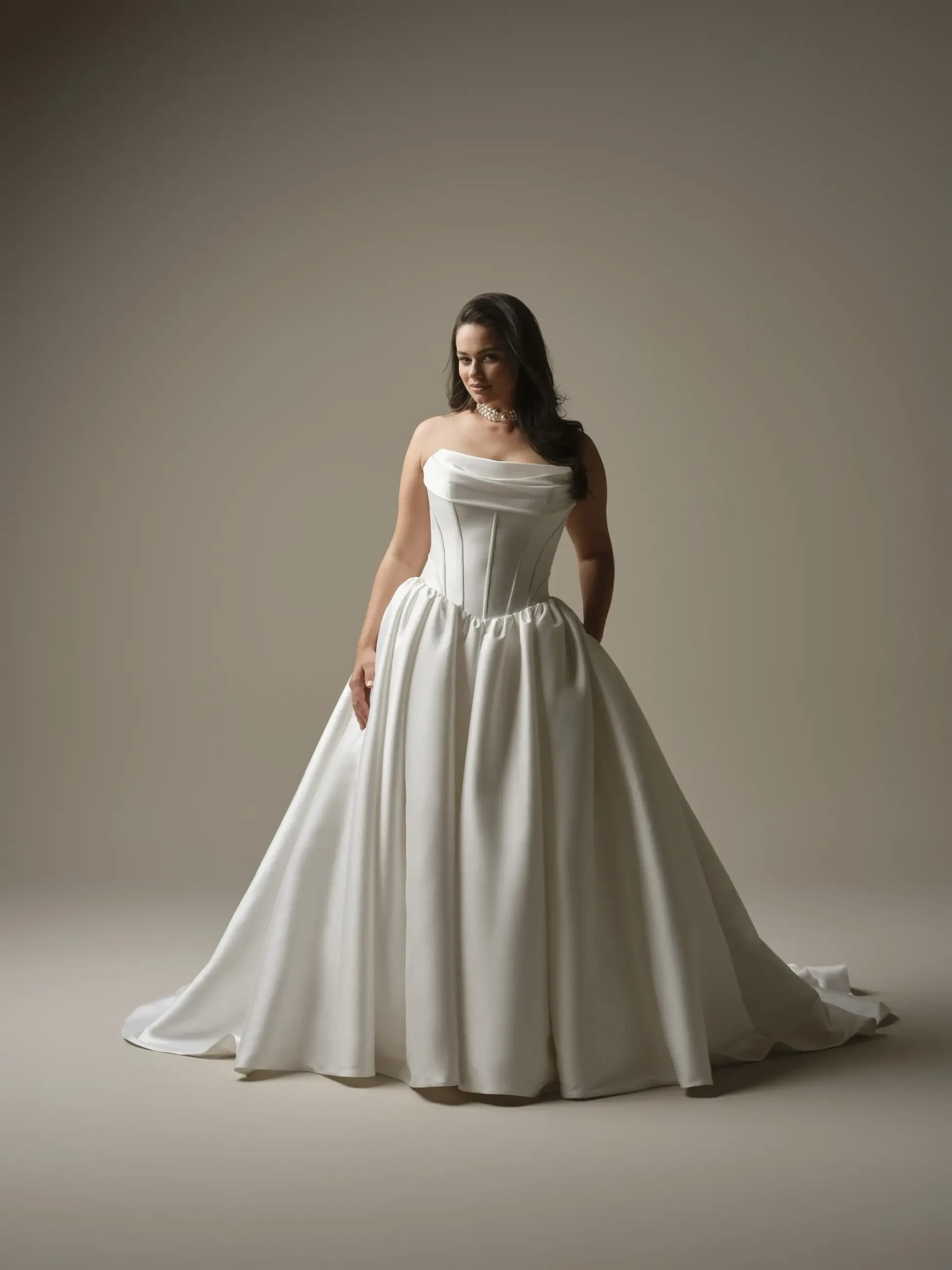 model is wearing a plus size strapless ball gown